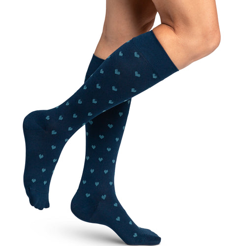Sigvaris Style Microfibre Patterns women's compression socks in Navy Hearts, worn by a model, right-side view